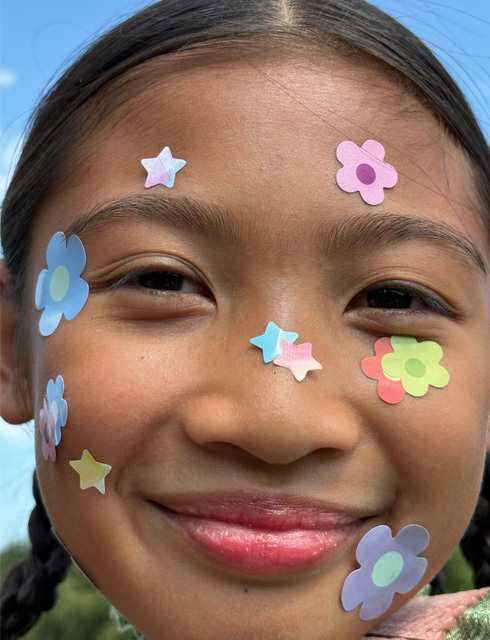 Fotografija djevojke u ultra krupnom planu s naljepnicama u obliku cvijeća na licu snimljena kontinuiranim zumom na iPhoneu 15